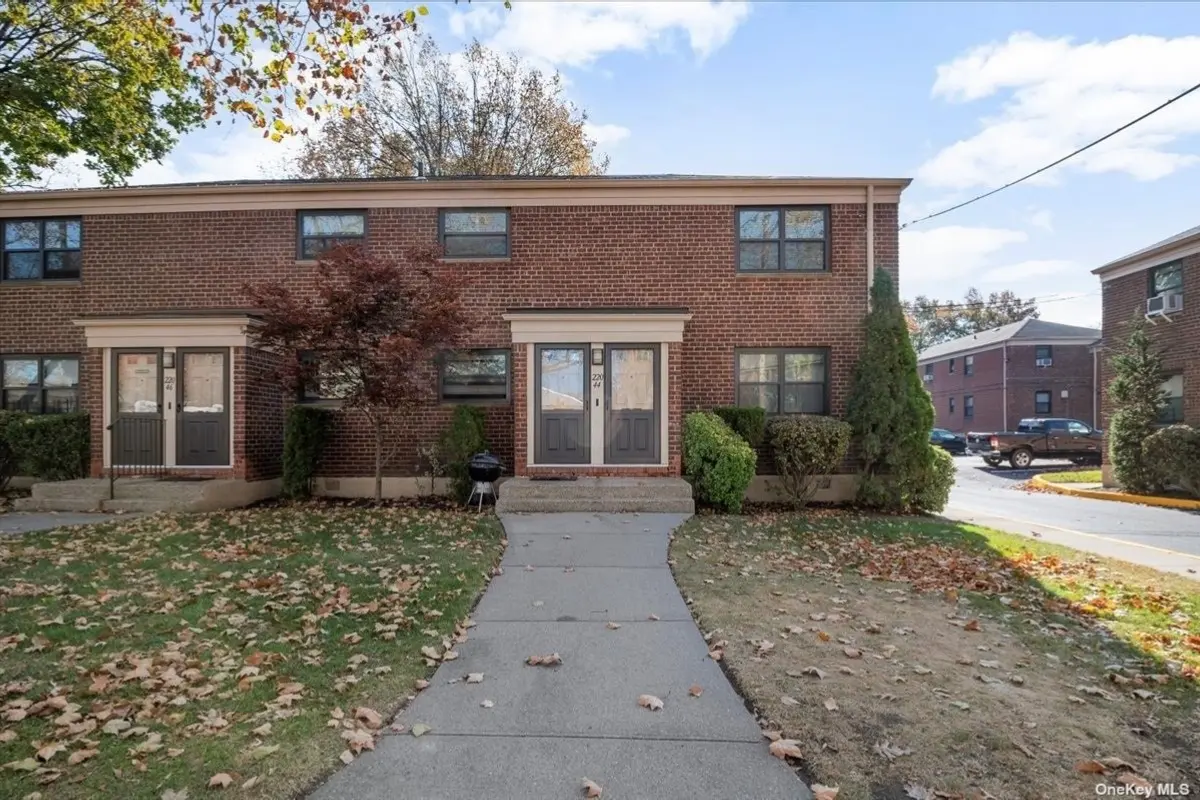 A brick building with two windows and a sidewalk.